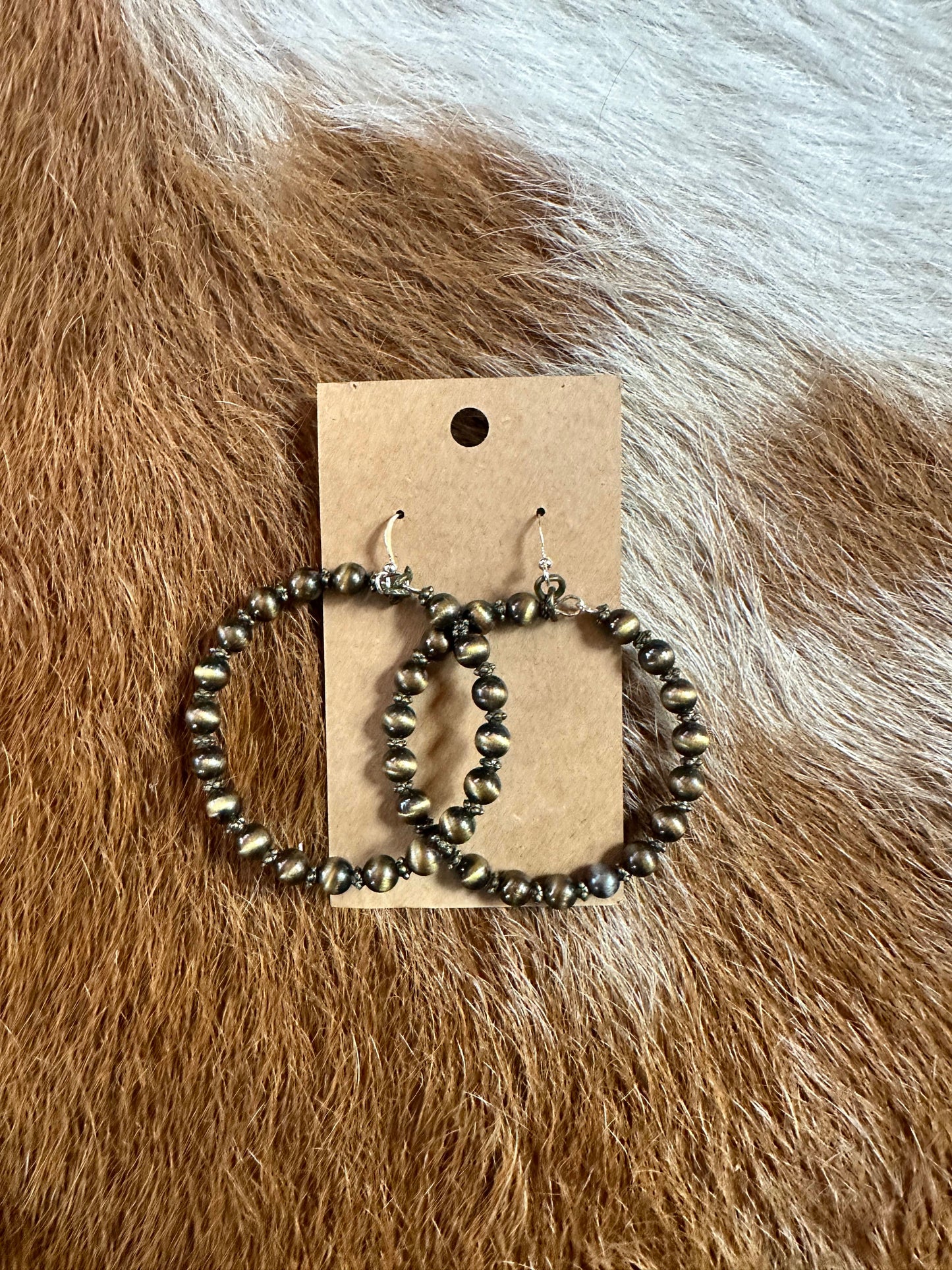 Hoop earrings with small beads on a brown background.