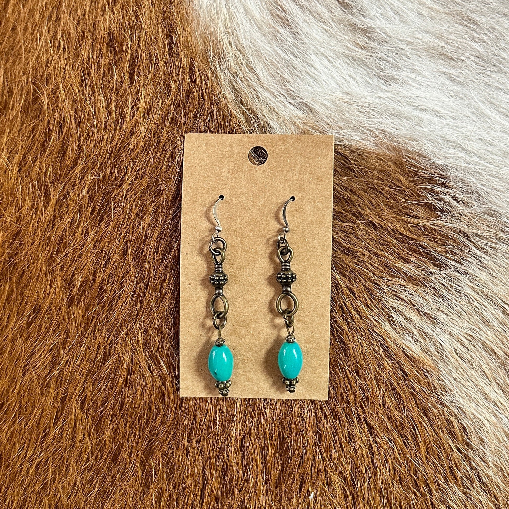 Earrings with turquoise beads on a brown tag.