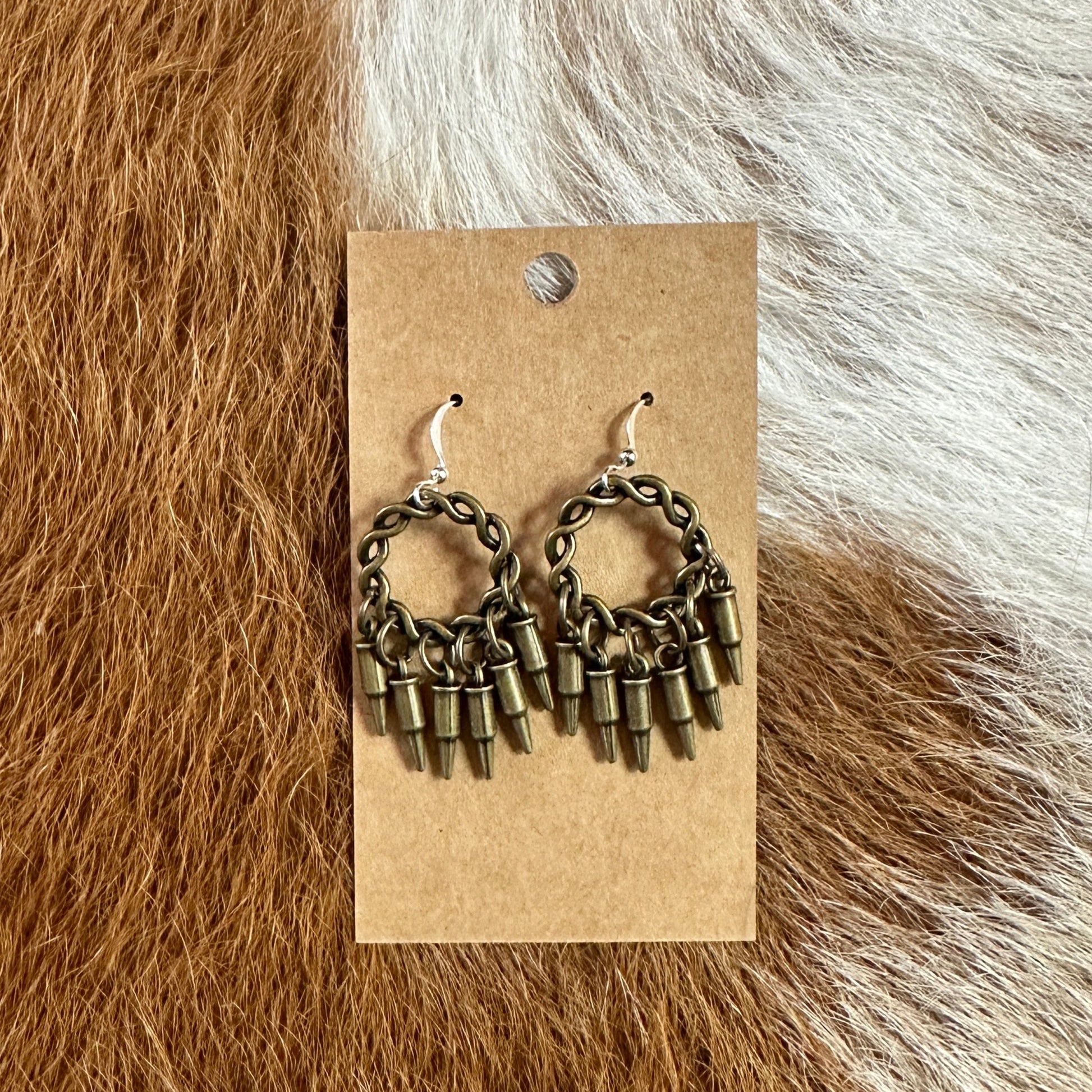 Earrings with bullet-shaped charms on a cardboard backing.