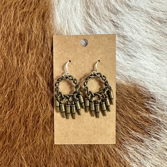 Earrings with bullet-shaped charms on a cardboard backing.