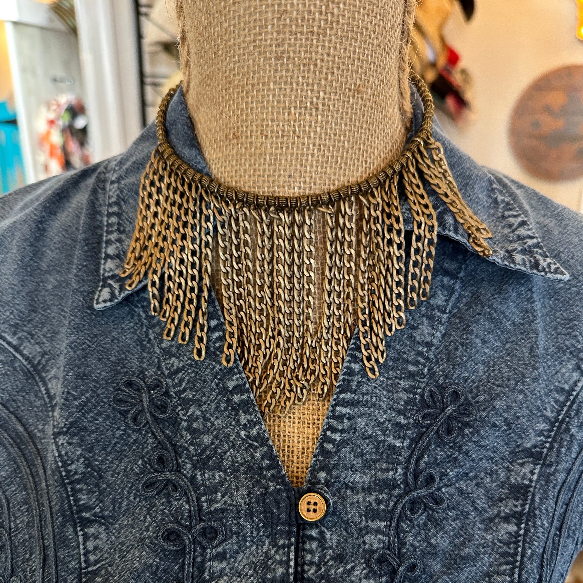 Gold chain fringe necklace on denim jacket.