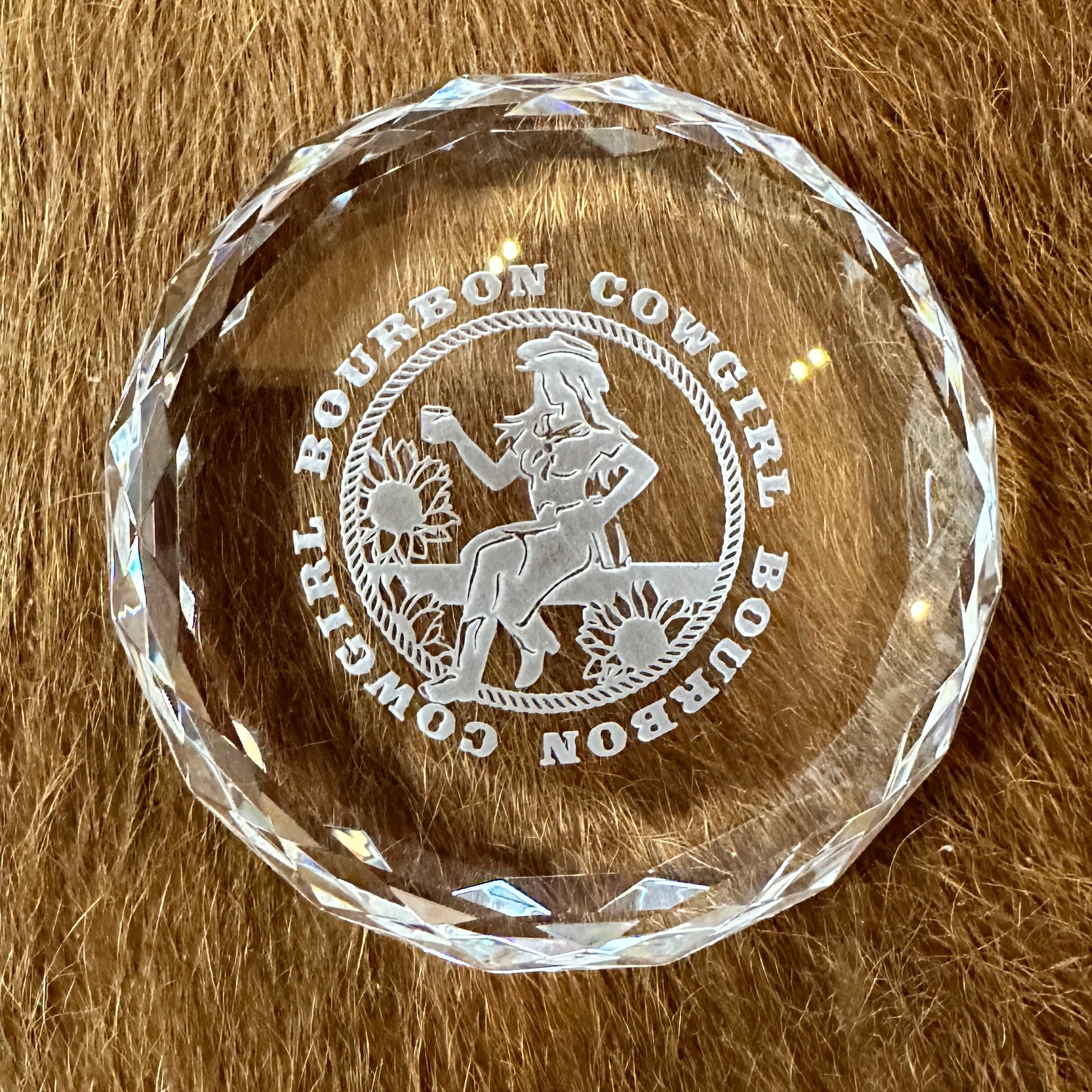 Round glass paperweight with Bourbon Cowgirl logo.
