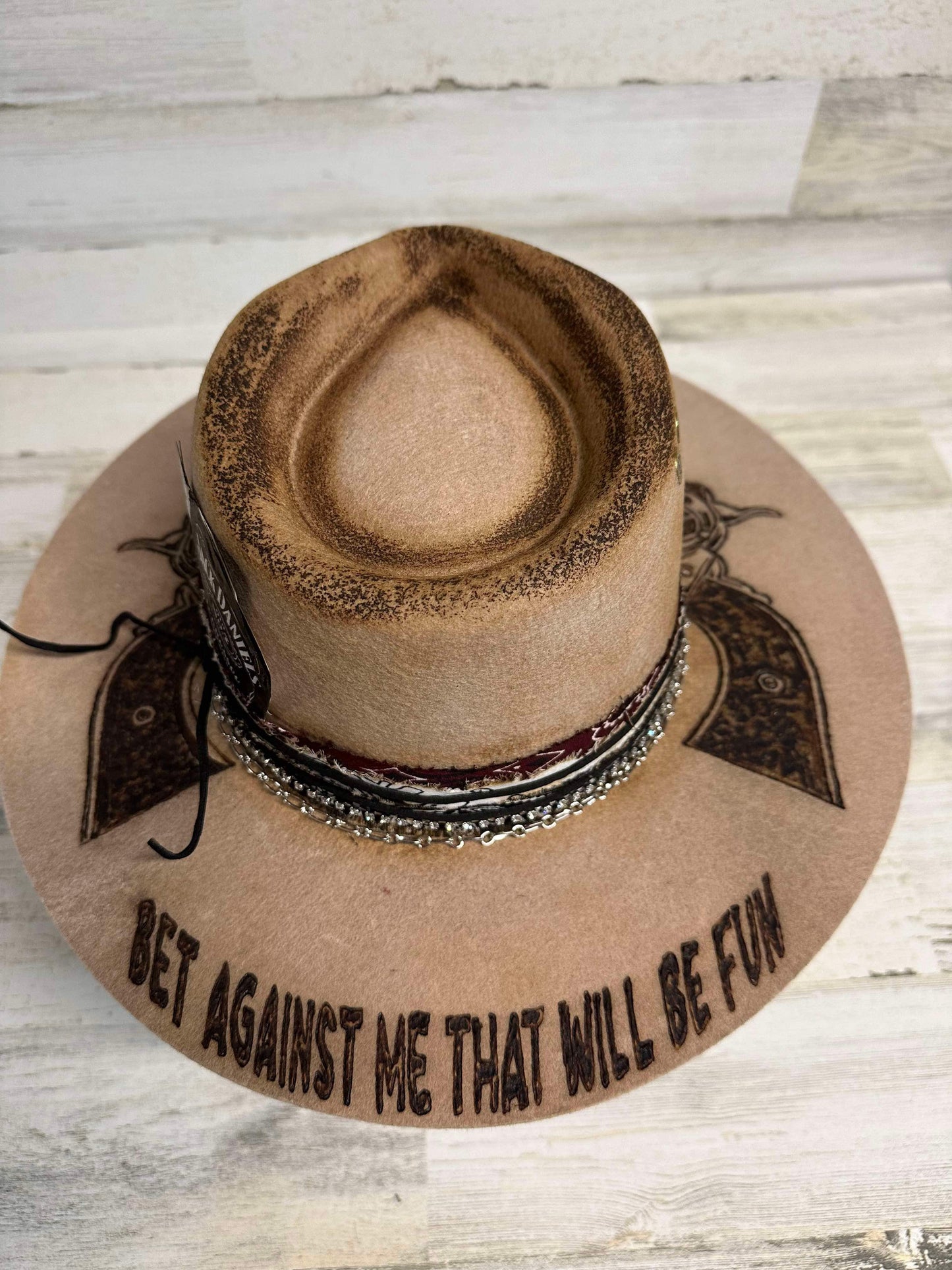 Cowboy hat with text and pistol design.