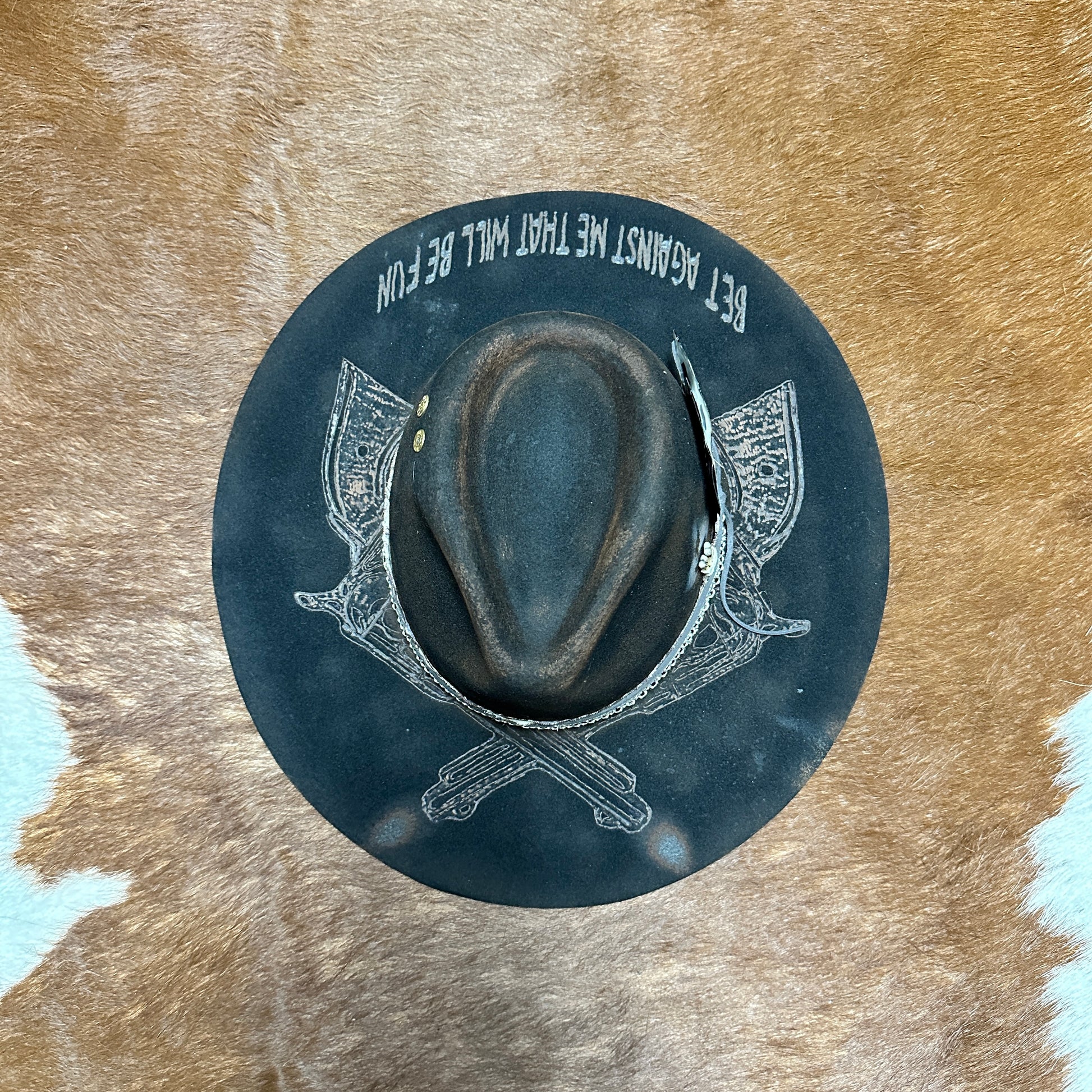 Dark hat with graphic on cowhide background.