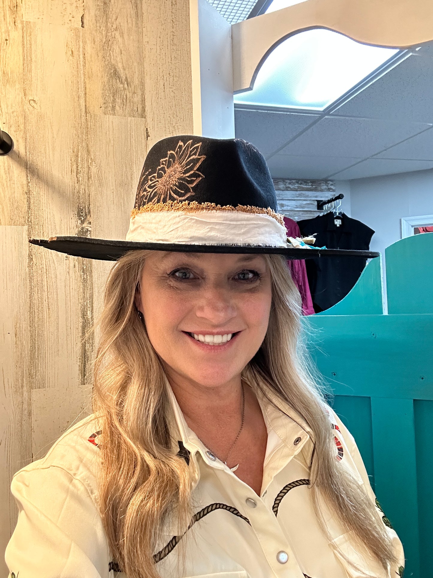 Woman wearing a black hat with a sunflower design.