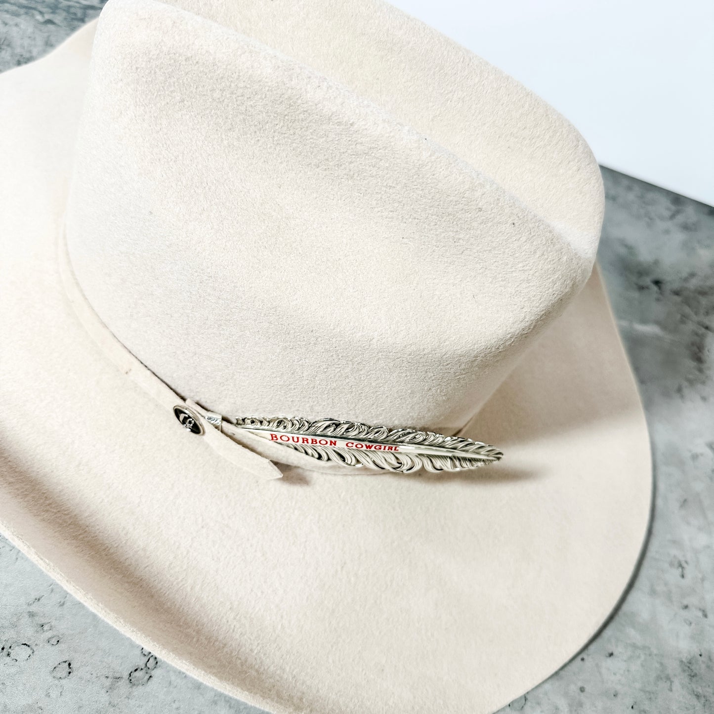 Cream-colored cowboy hat with feather pin.