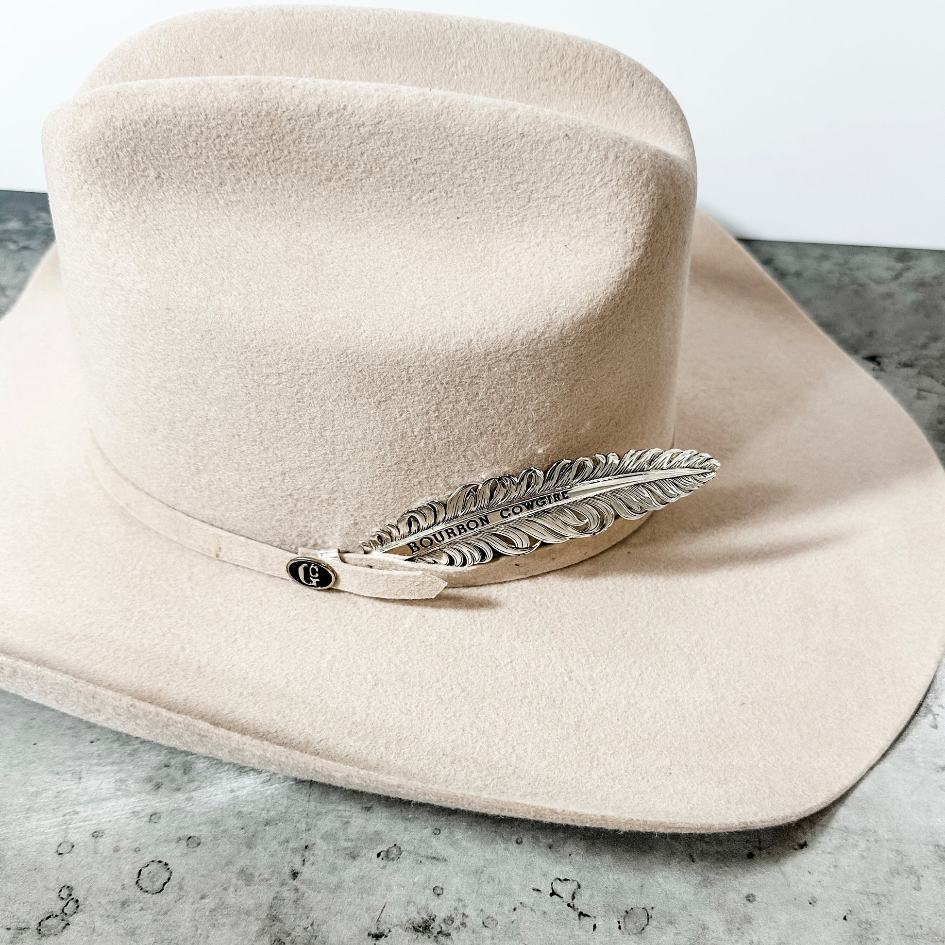 Cream-colored cowboy hat with feather accent.
