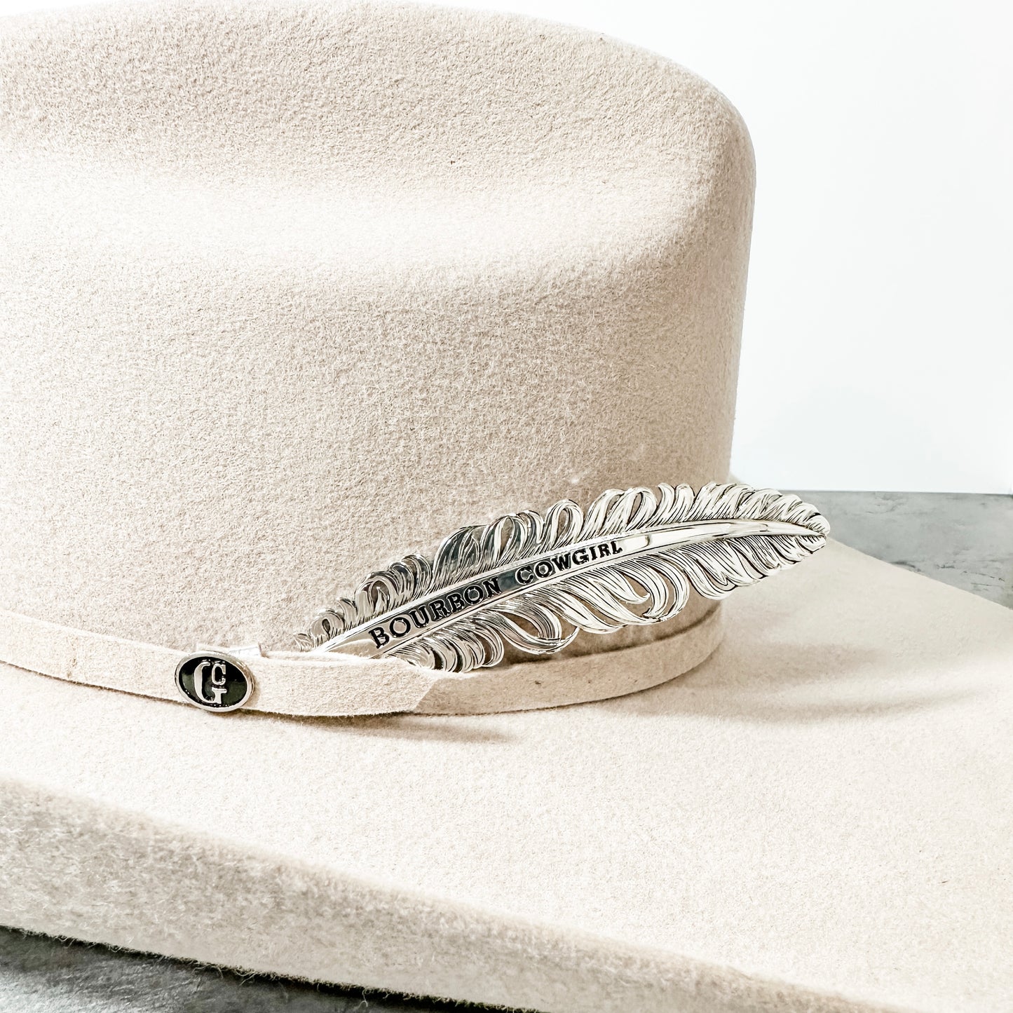Tan cowboy hat with feather pin.