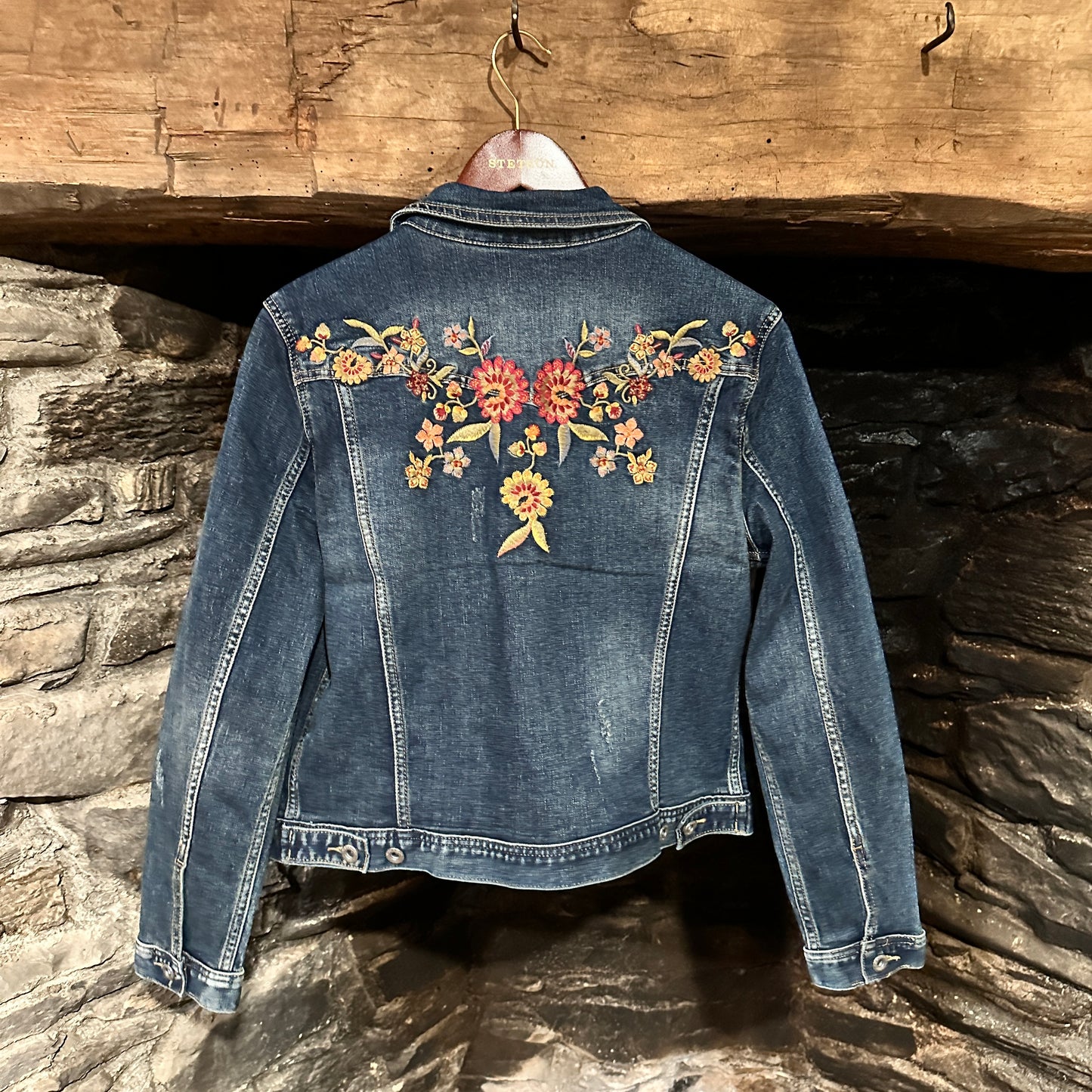 Blue denim jacket with floral embroidery.