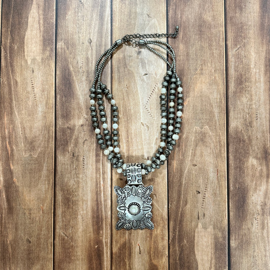 Silver beaded necklace with ornate pendant.