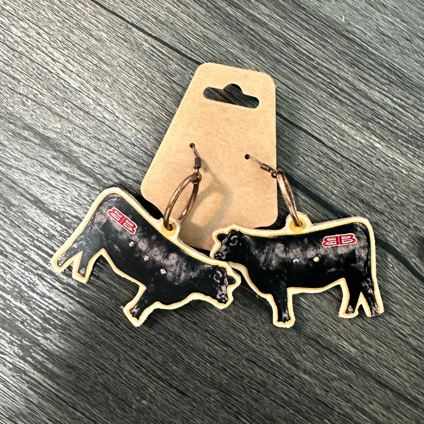 Cow-shaped earrings on a cardboard backing.