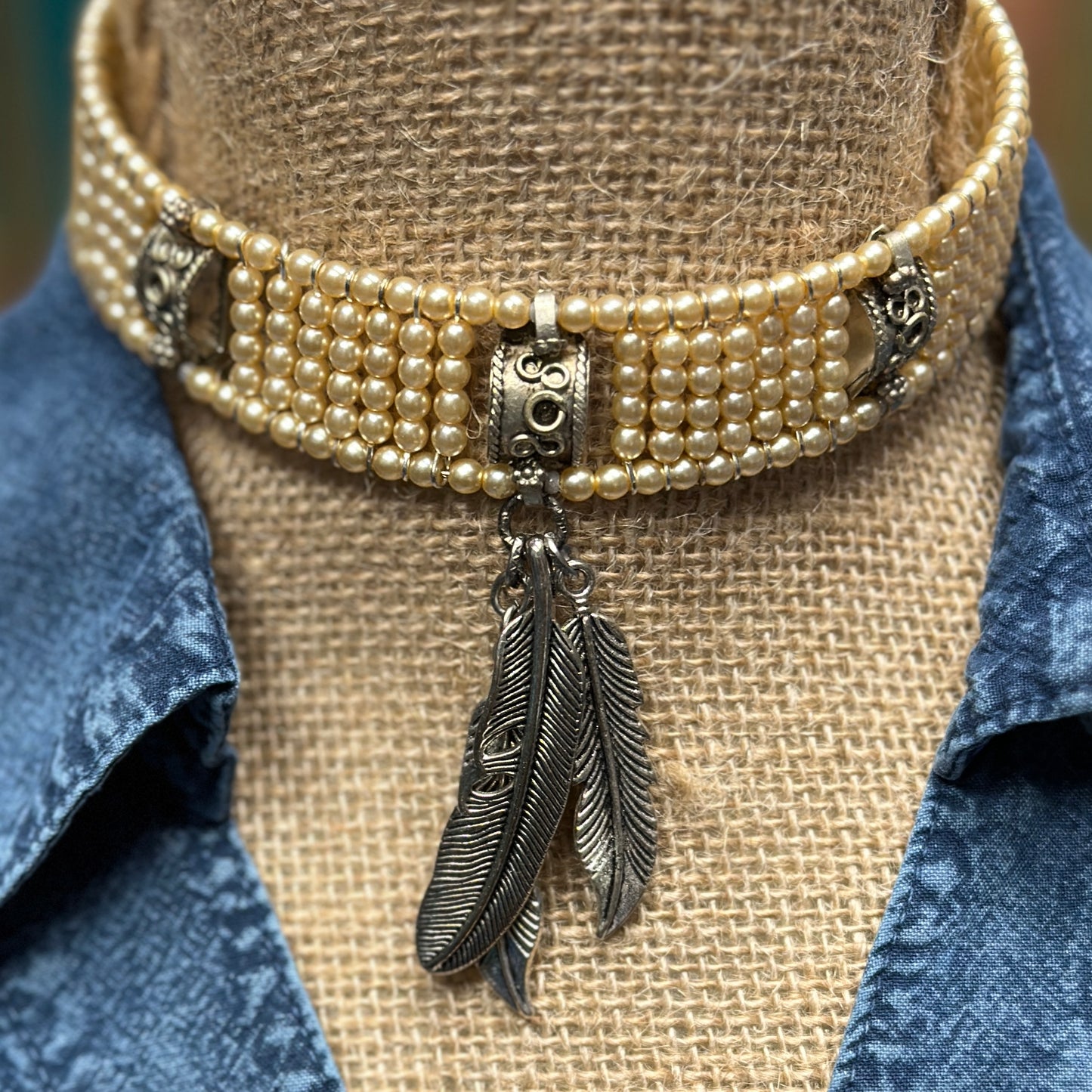 Pearl choker necklace with feather pendant.