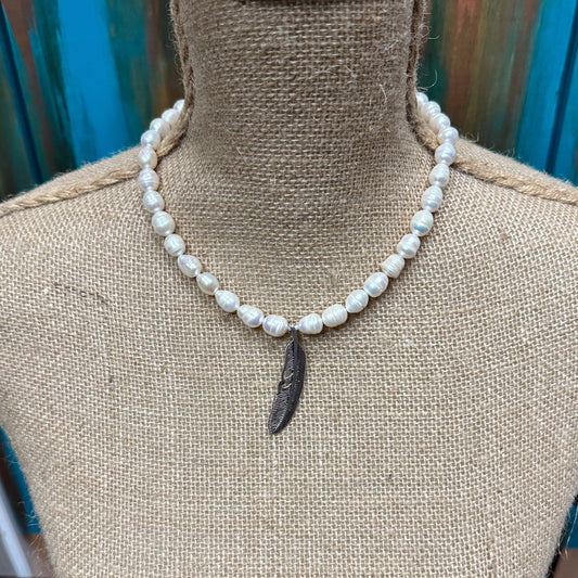 Pearl necklace with pendant on a bust.