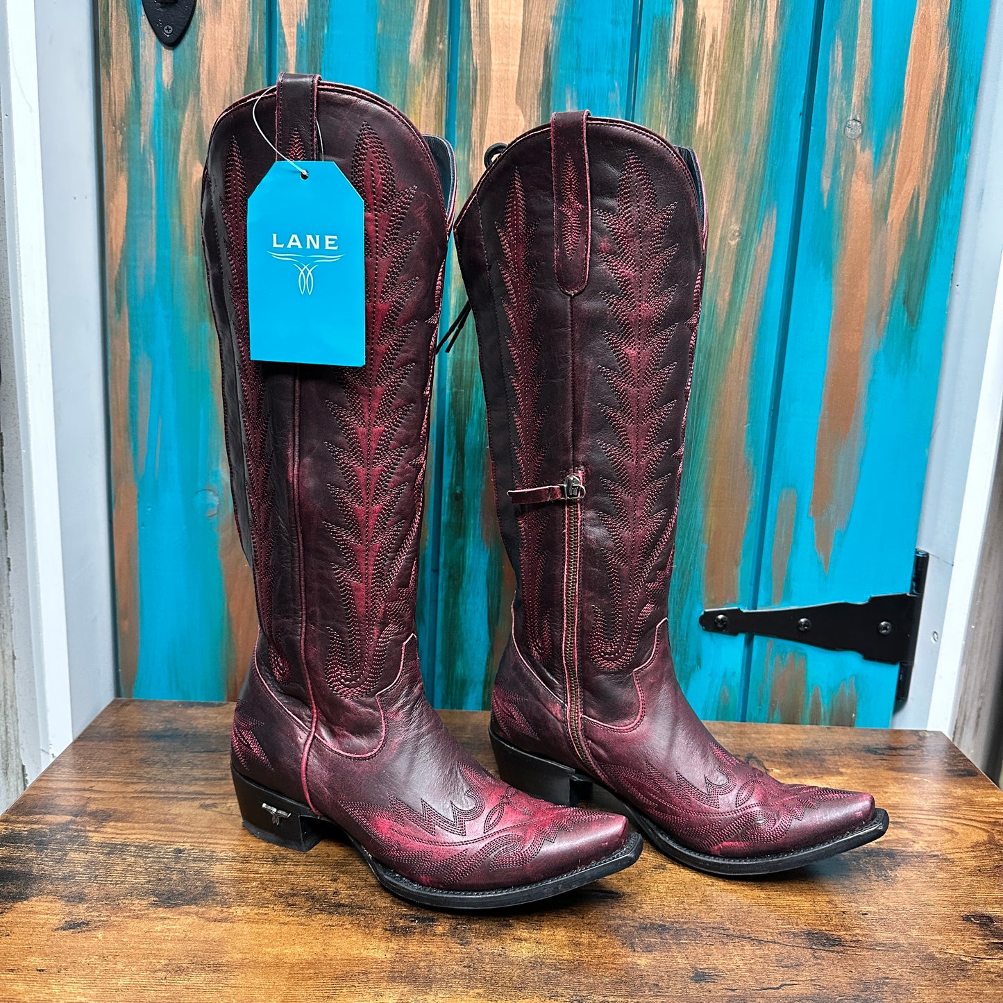 Pair of tall, red cowboy boots with tags.