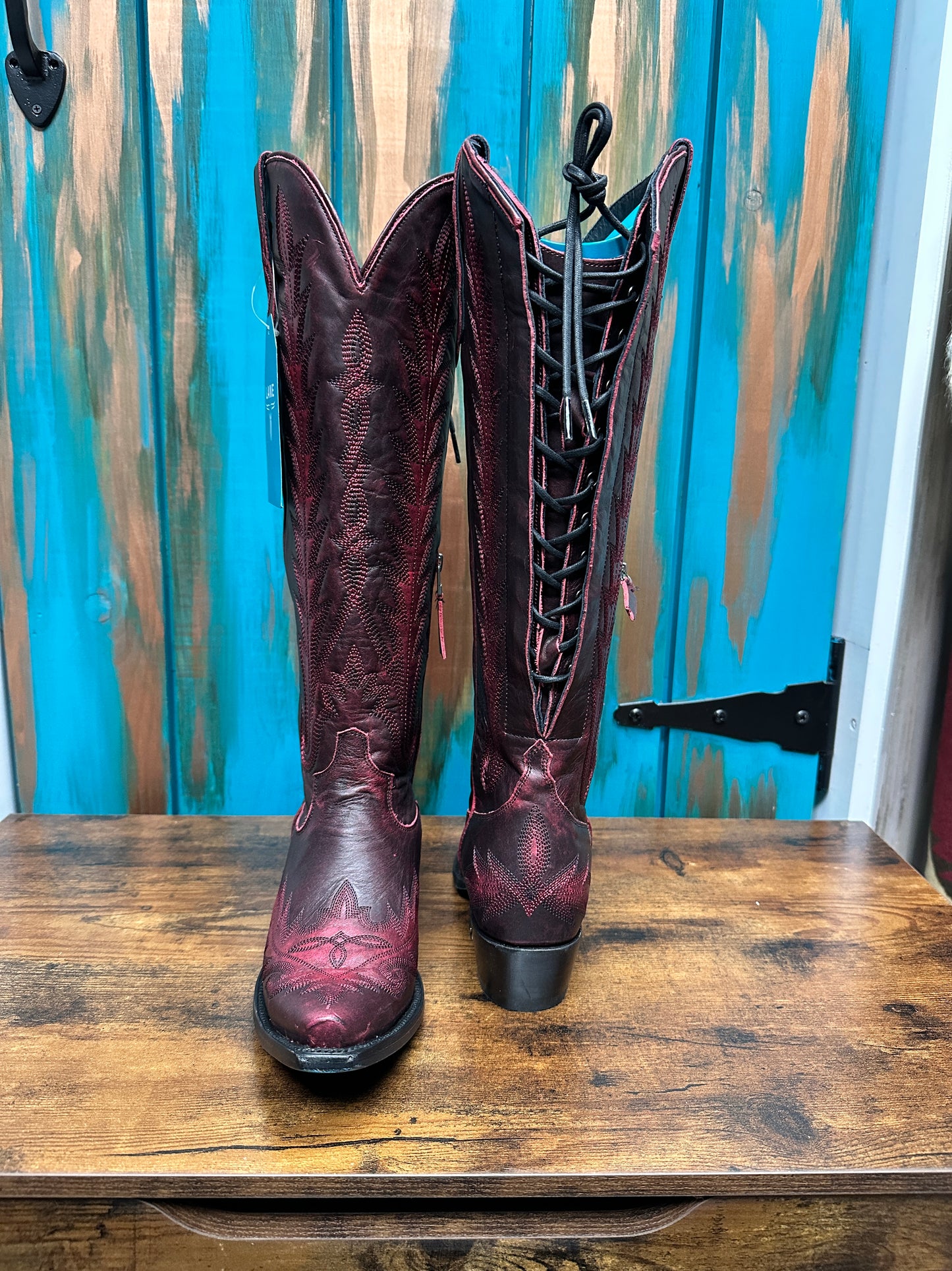 Red leather cowboy boots on wooden surface.