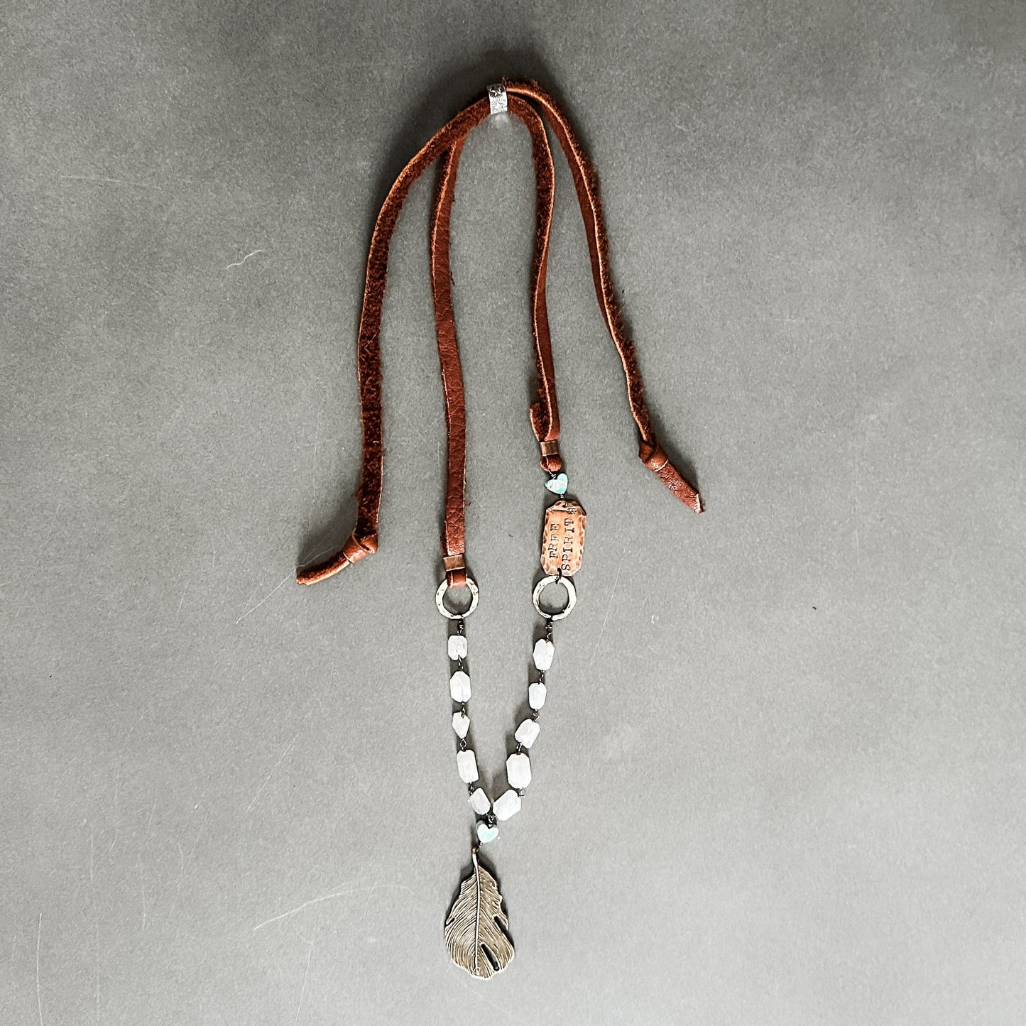Leather necklace with feather pendant.