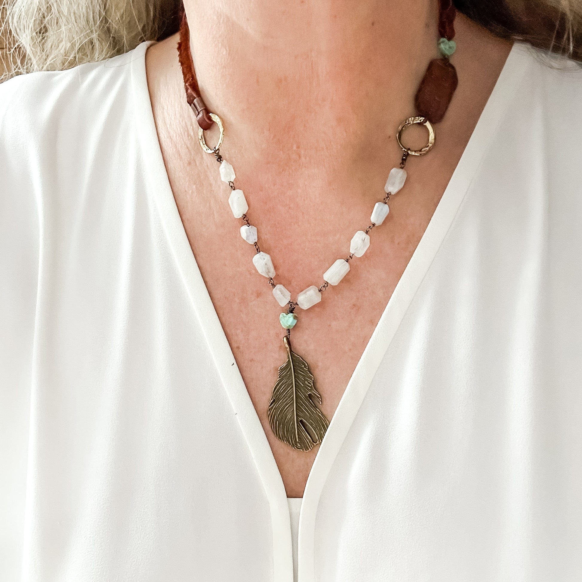 Woman wearing a necklace with a feather pendant.