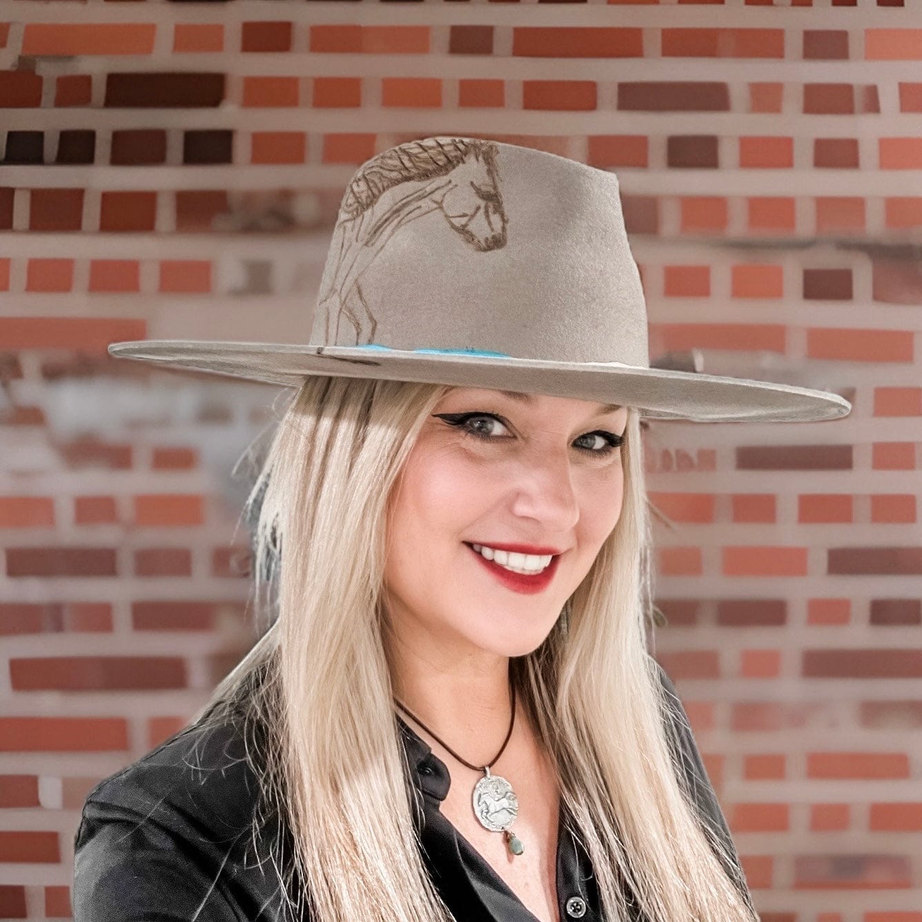 Woman wearing a hat with a horse design, smiling.