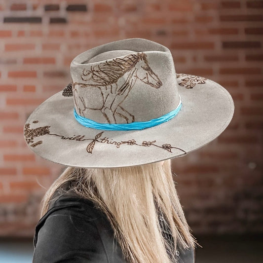 Woman wearing a grey hat with horse illustration.