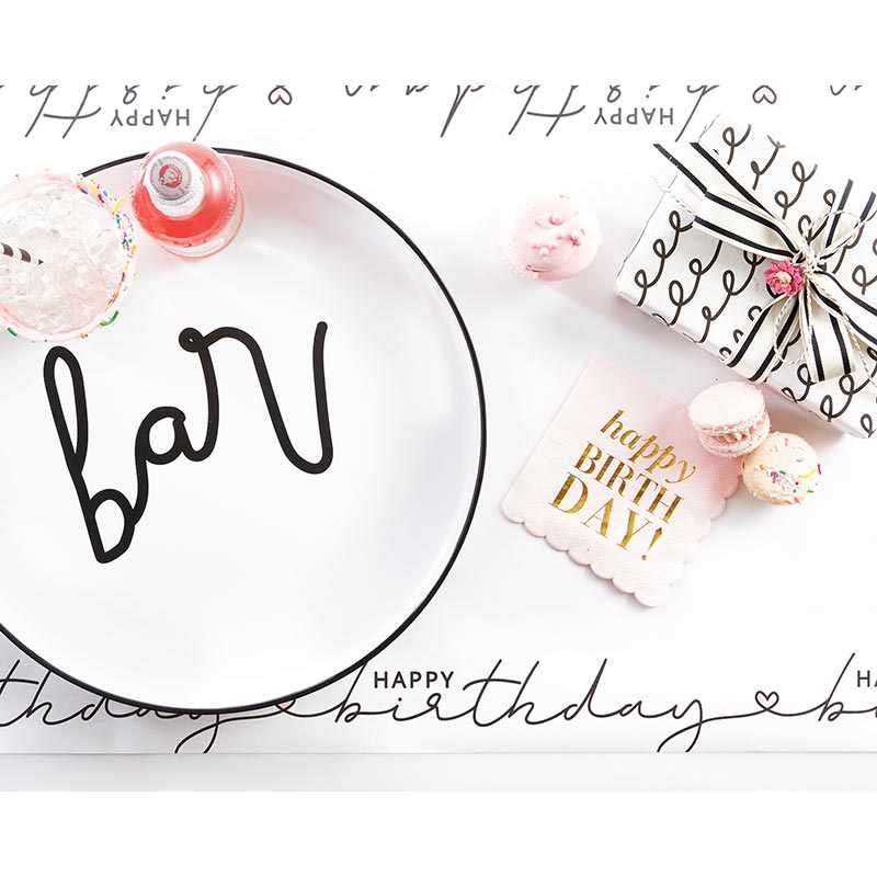 Birthday table setting with bar plate, gifts, and treats.
