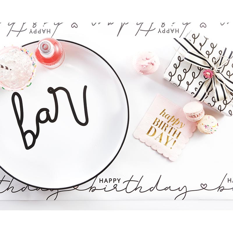 Birthday table setting with bar plate, gifts, and treats.