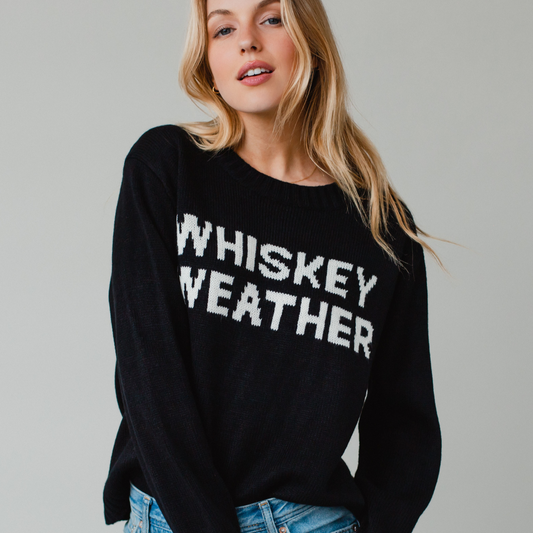 Woman wearing a black sweater with Whiskey Weather in white text.