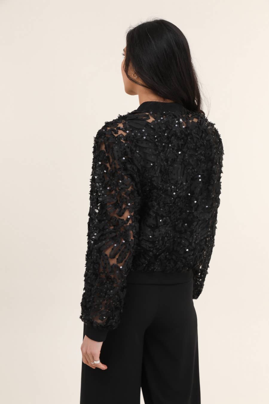 Woman wearing a black sequined jacket from behind.