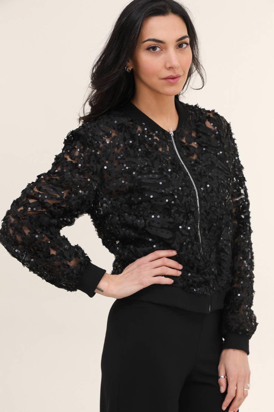 Woman wearing a black sequin bomber jacket.