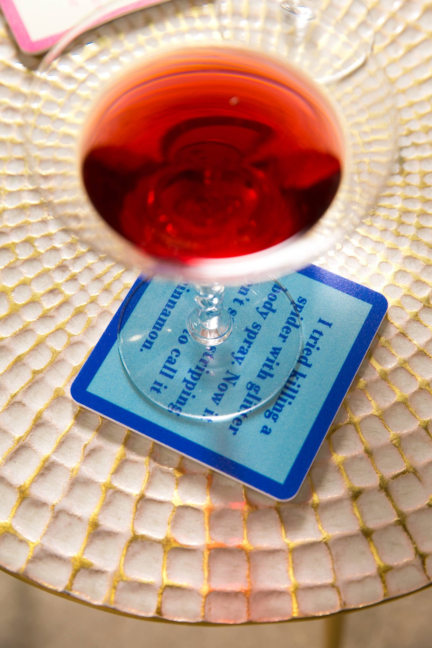 Wine glass over coaster with text about killing a spider.
