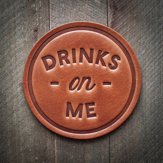 Leather coaster with DRINKS on ME text.