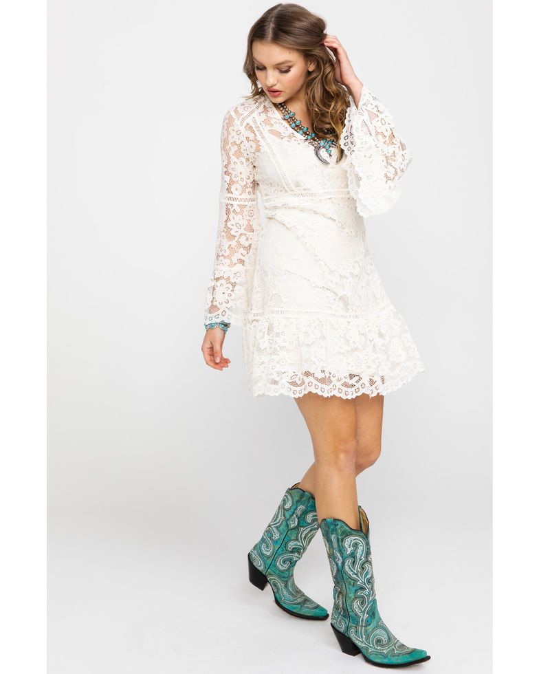 Woman in white lace dress and turquoise boots.