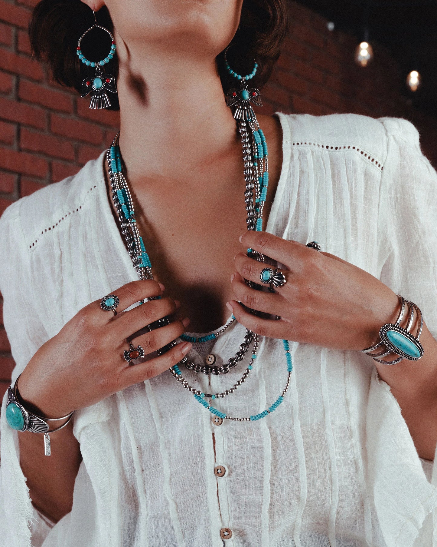 Woman wearing turquoise jewelry and white shirt, lifestyle image