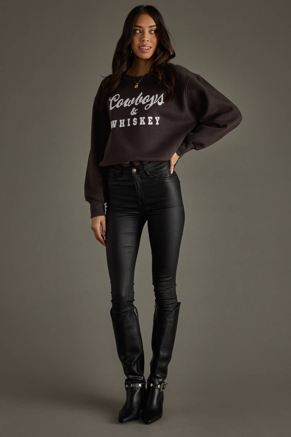 Woman in sweatshirt and black pants and boots.