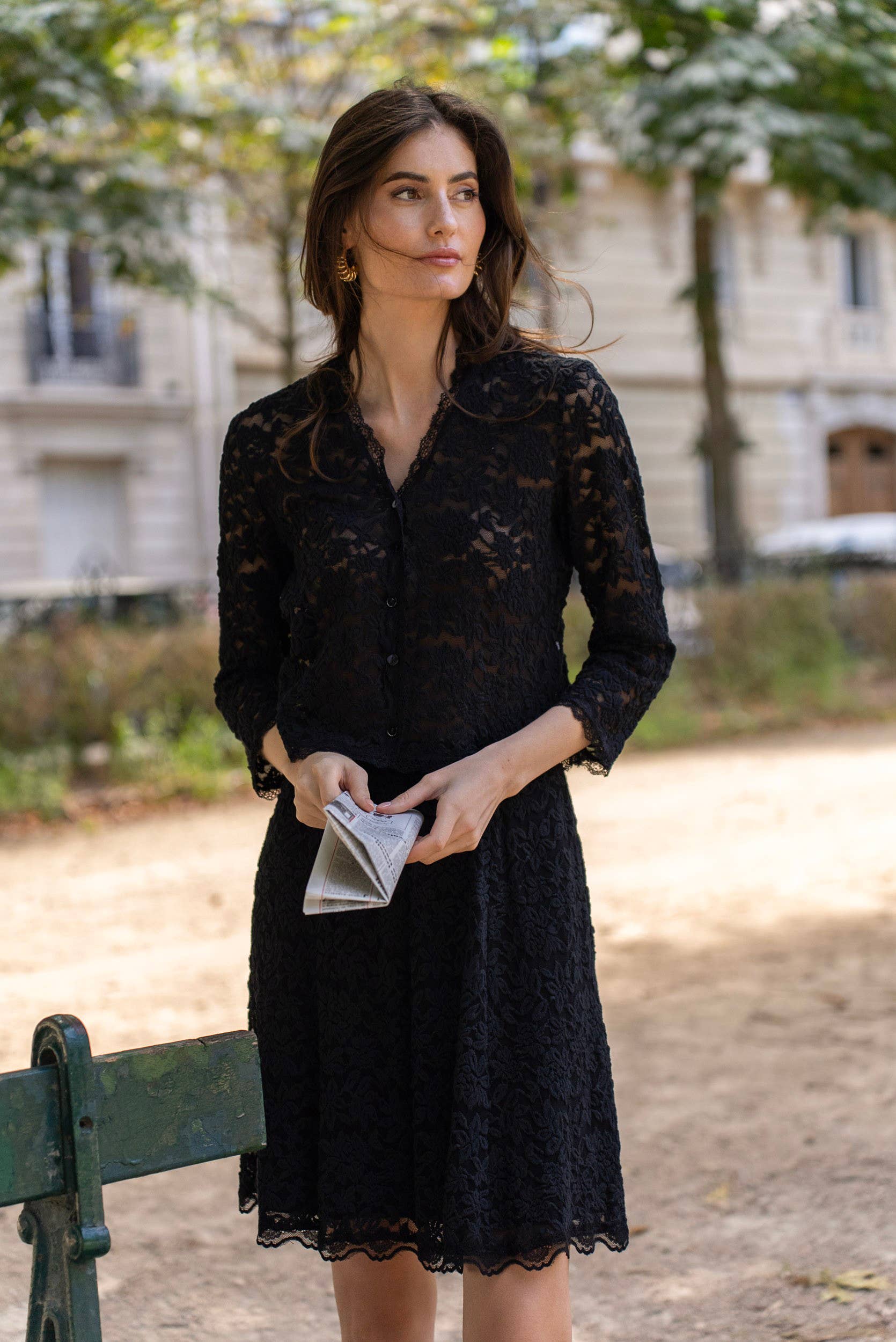 Woman in black lace dress holding a folded paper.