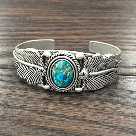Silver cuff bracelet with turquoise stone and feather design.