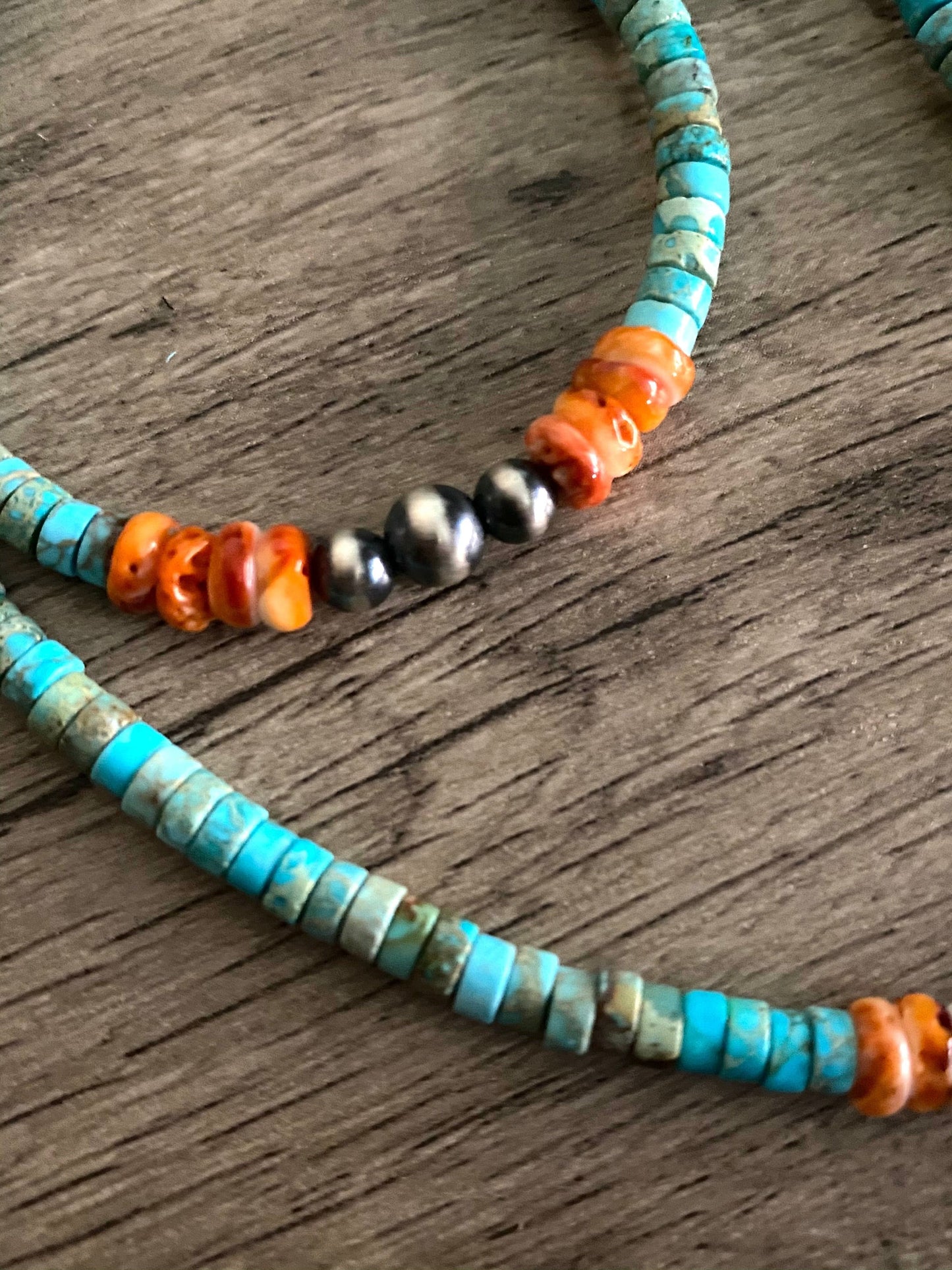 Turquoise beaded necklace with orange and silver accents.