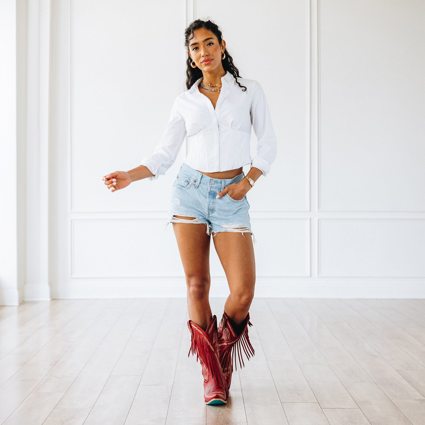 Woman in white shirt, denim shorts, and ruby red boots