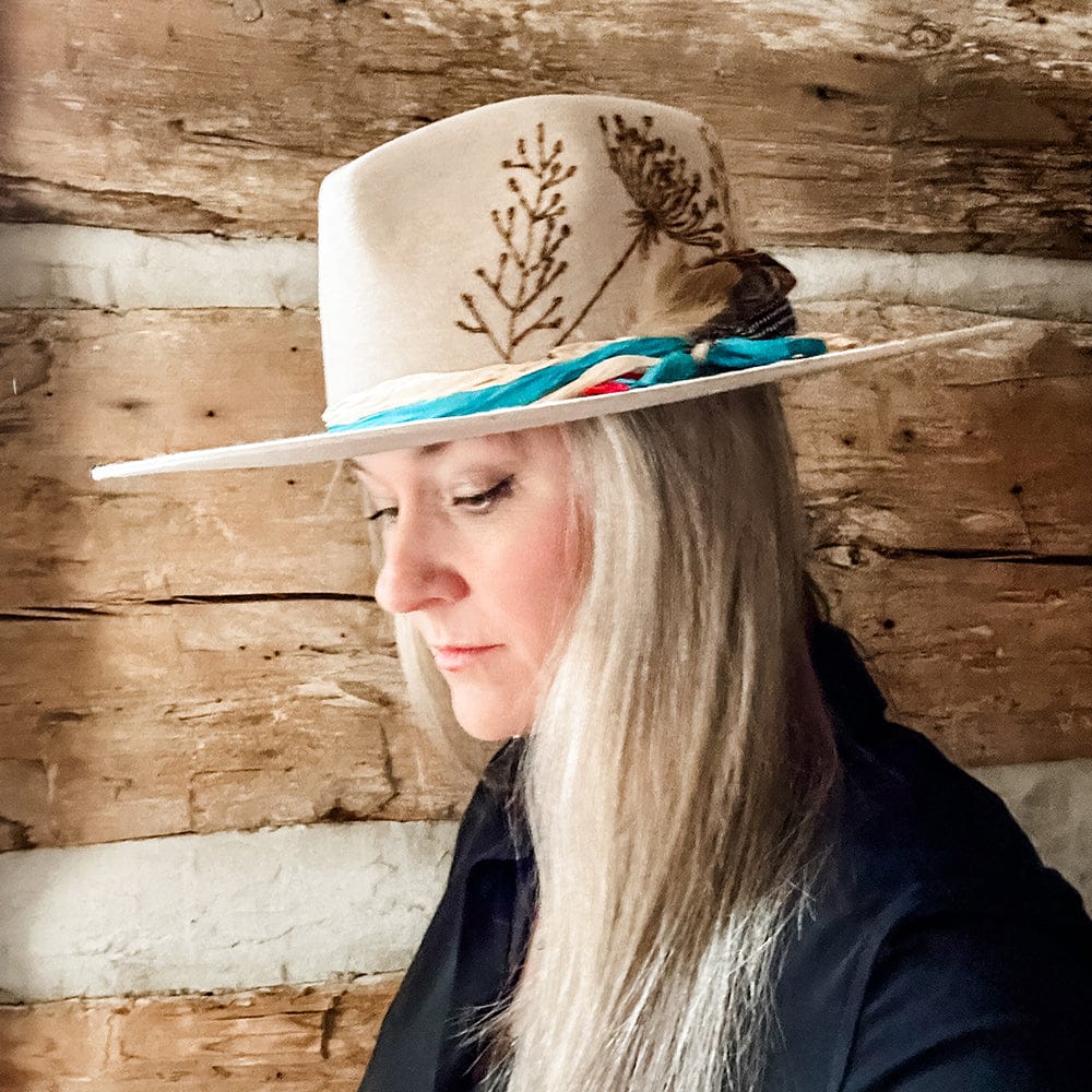 Woman wearing tan hat with floral embroidery