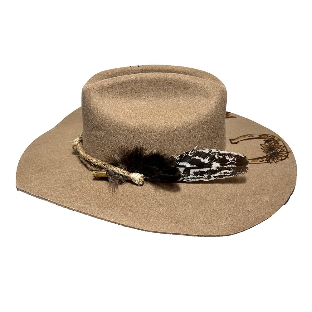Tan cowboy hat with feather and horseshoe detail.