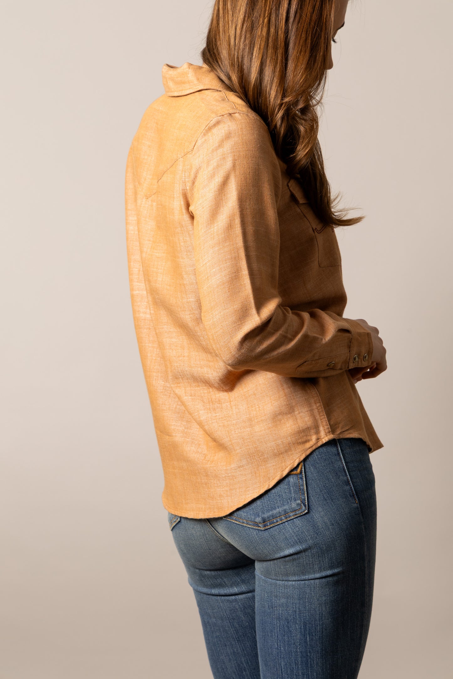 Woman in tan button-up shirt and jeans