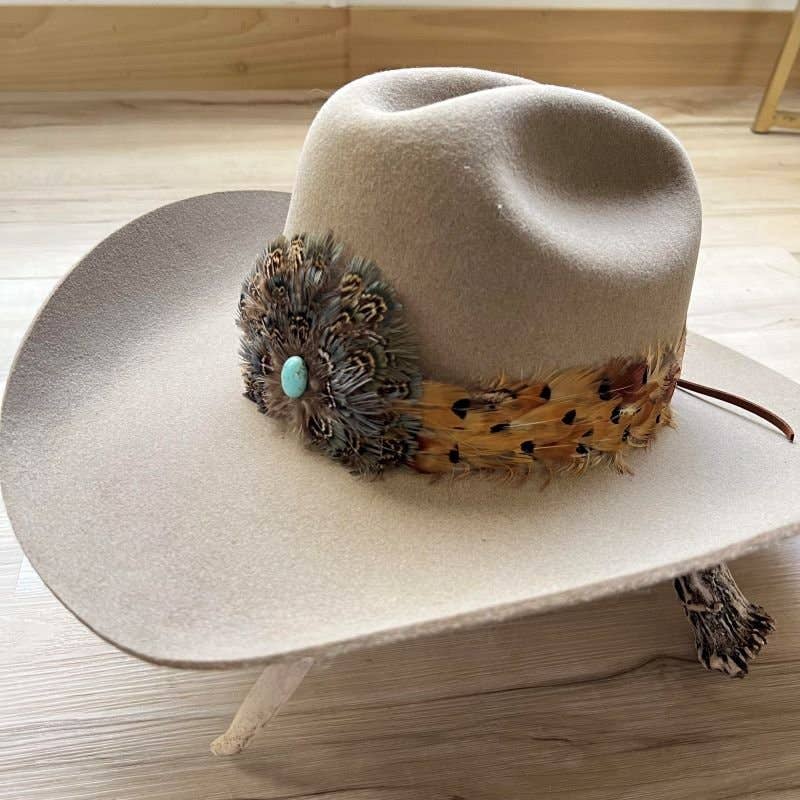 Beige cowboy hat with feather and turquoise detail.
