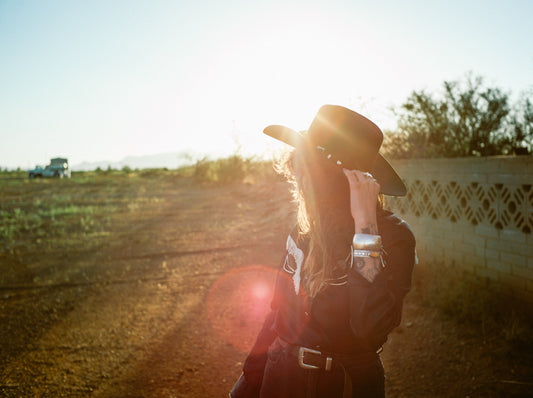 woman wearing the best denim jeans for traditional Western wear alongside a cowboy hat and top