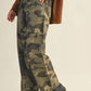 Person wearing camouflage pants and brown sweater.