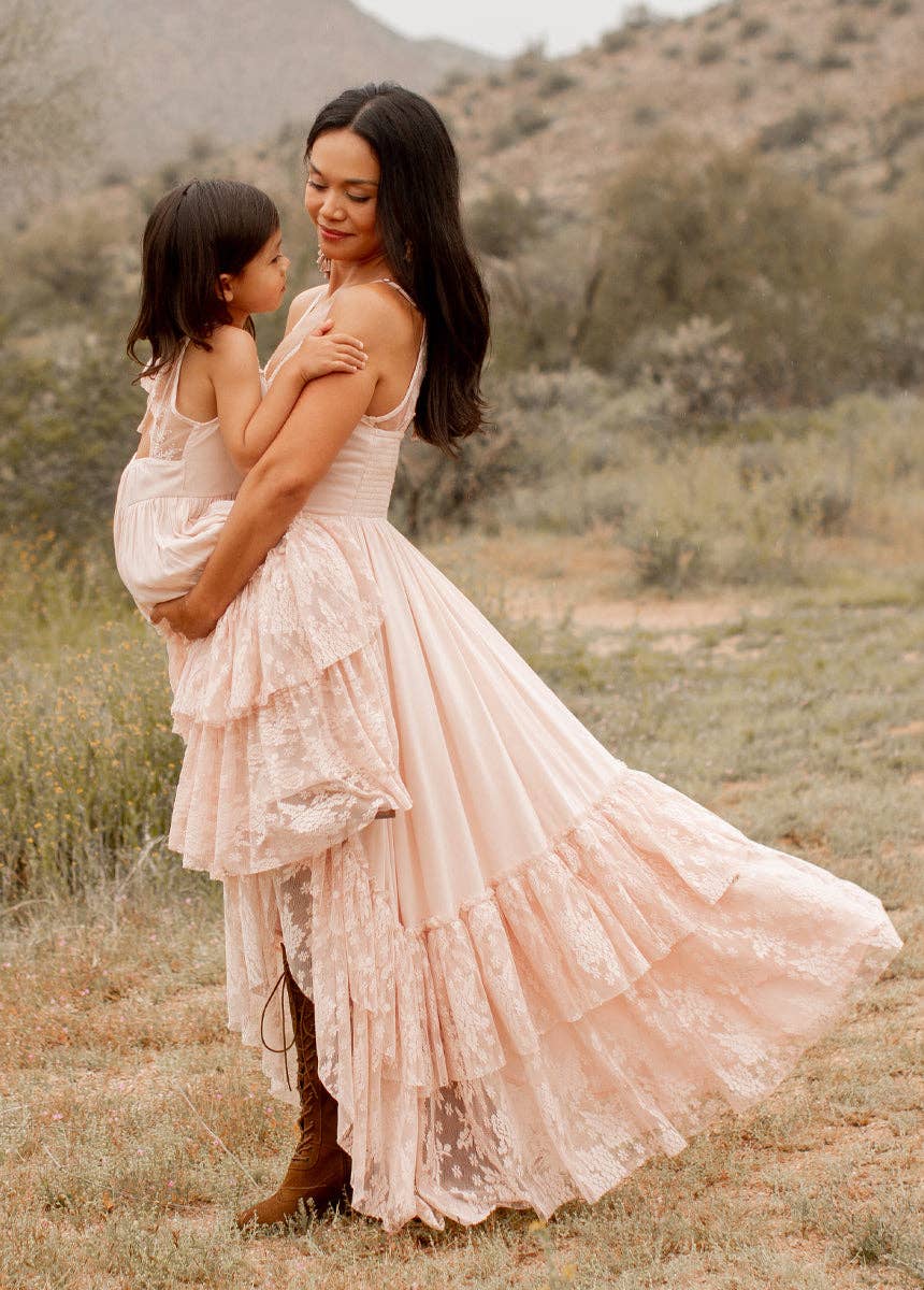 Woman holding a child, both wearing pink dresses.