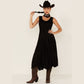 Woman in black dress, cowboy hat, and boots.