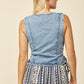 Woman wearing denim vest and patterned pants.