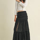 Woman wearing a white shirt and long black skirt.