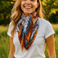 Woman smiling, wearing a patterned silk scarf and white t-shirt.