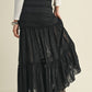 Woman wearing a black lace maxi skirt and white top.