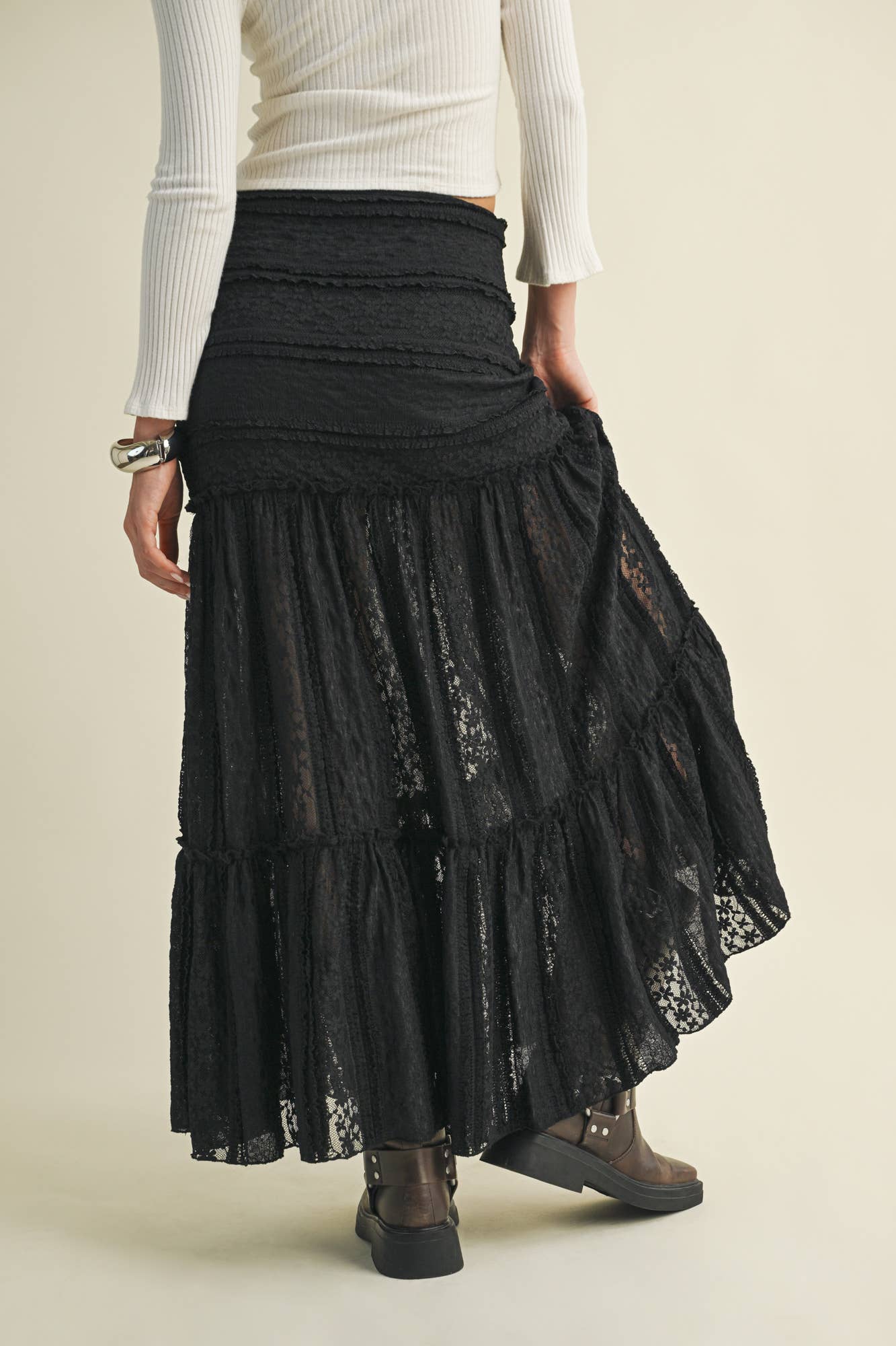 Woman wearing a black lace maxi skirt and white top.